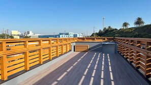A rooftop terrace with wooden railings, a concrete floor, and a view of buildings and trees in the background. - Solana Kisarazu (Kisarazu)