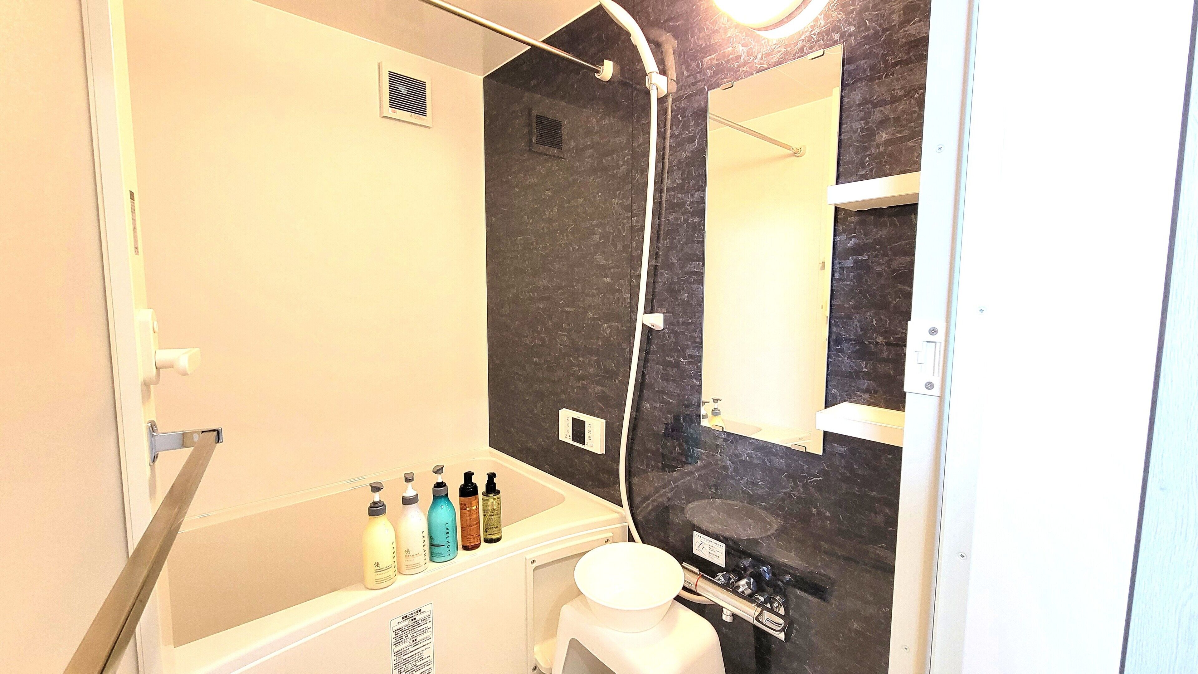 A bathroom with a bathtub, a shower, a toilet, and a sink. There are toiletries on the sink.