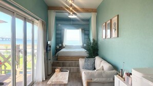 Amplia sala de estar con un gran ventanal con vistas panorámicas, un sofá acogedor, una mesa de centro de madera y una escalera que lleva a un dormitorio.