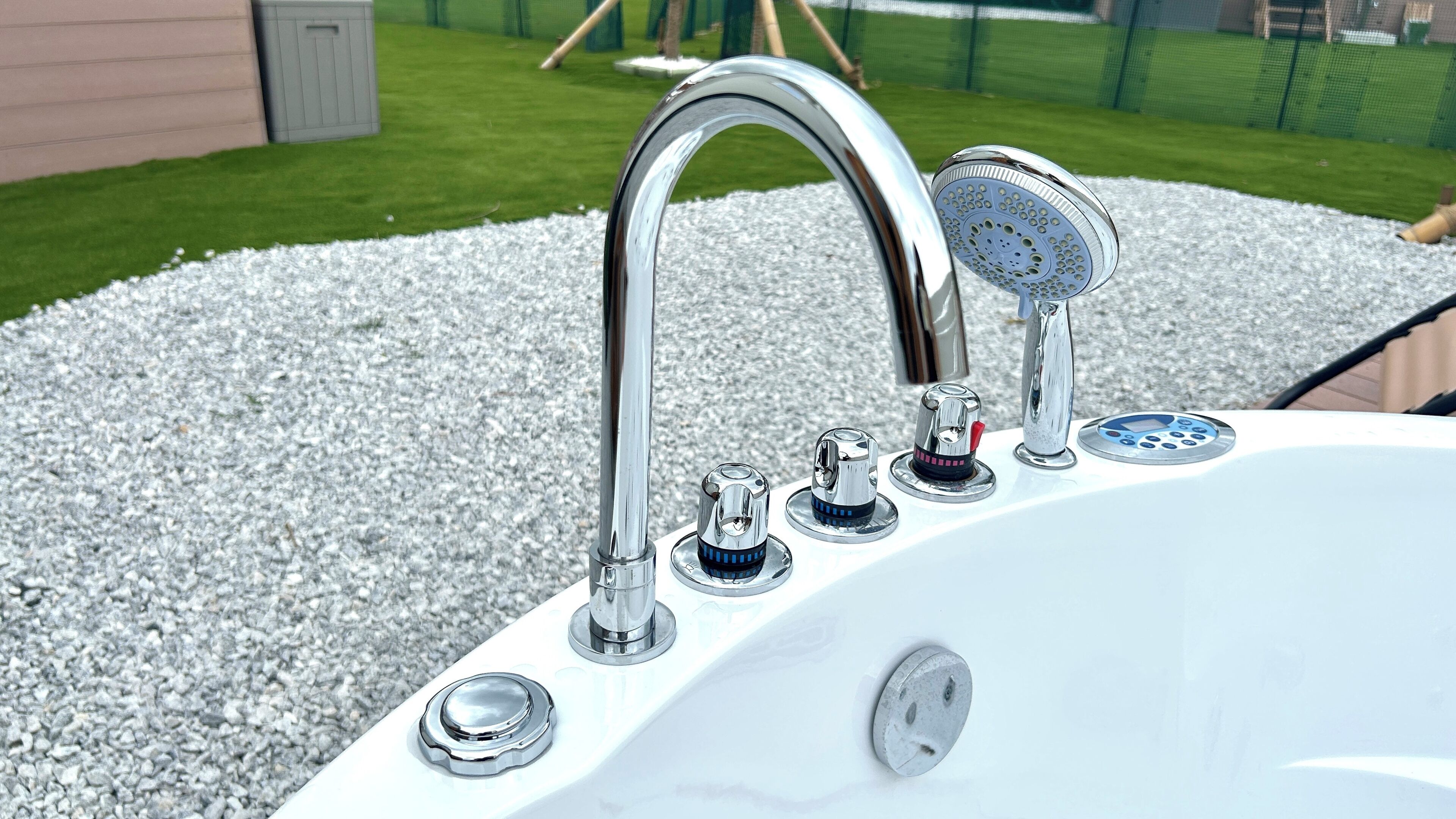 Un jacuzzi exterior blanco con múltiples grifos y un panel de control.