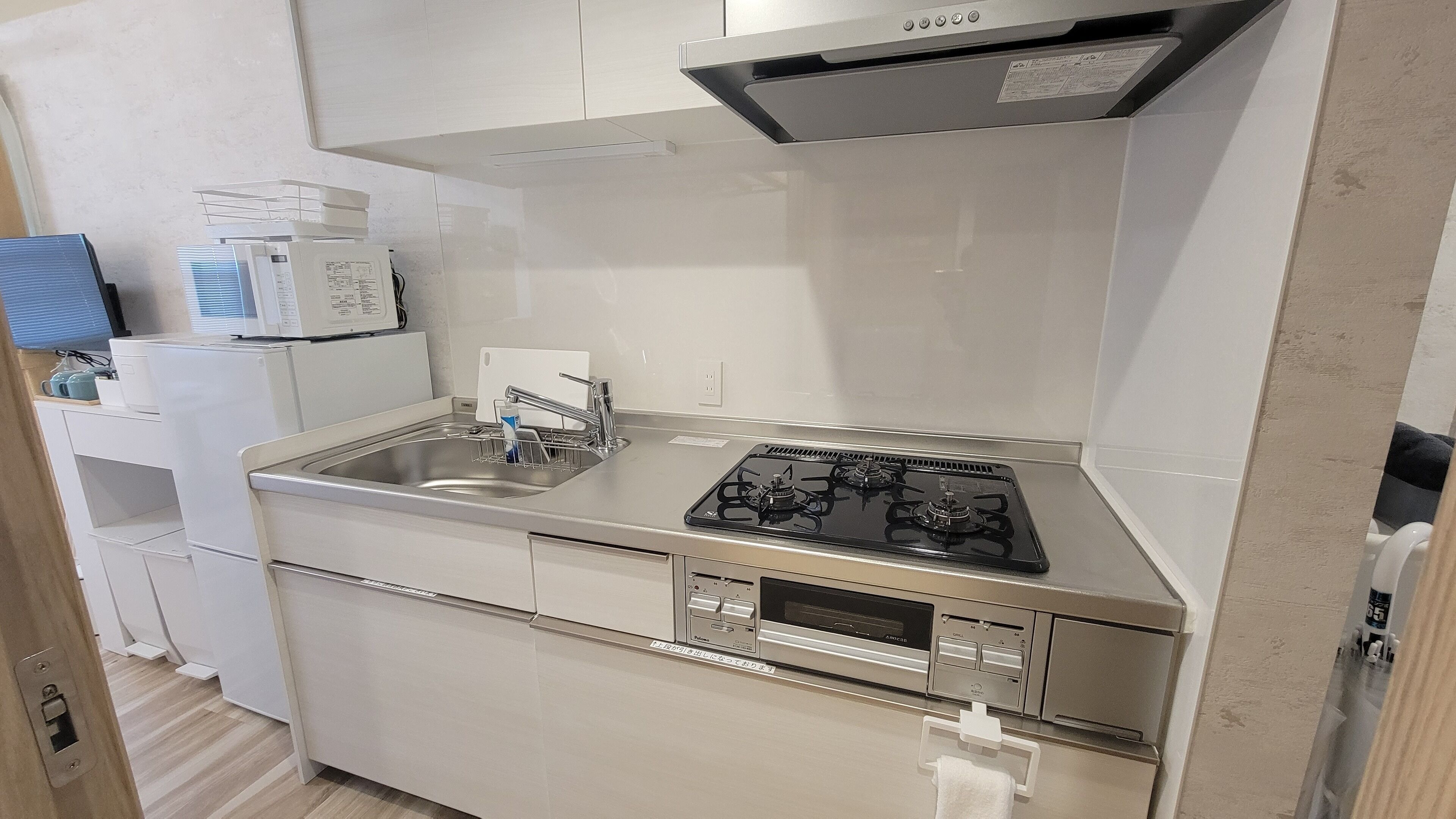 Uma cozinha compacta com fogão a gás, micro-ondas e pia.