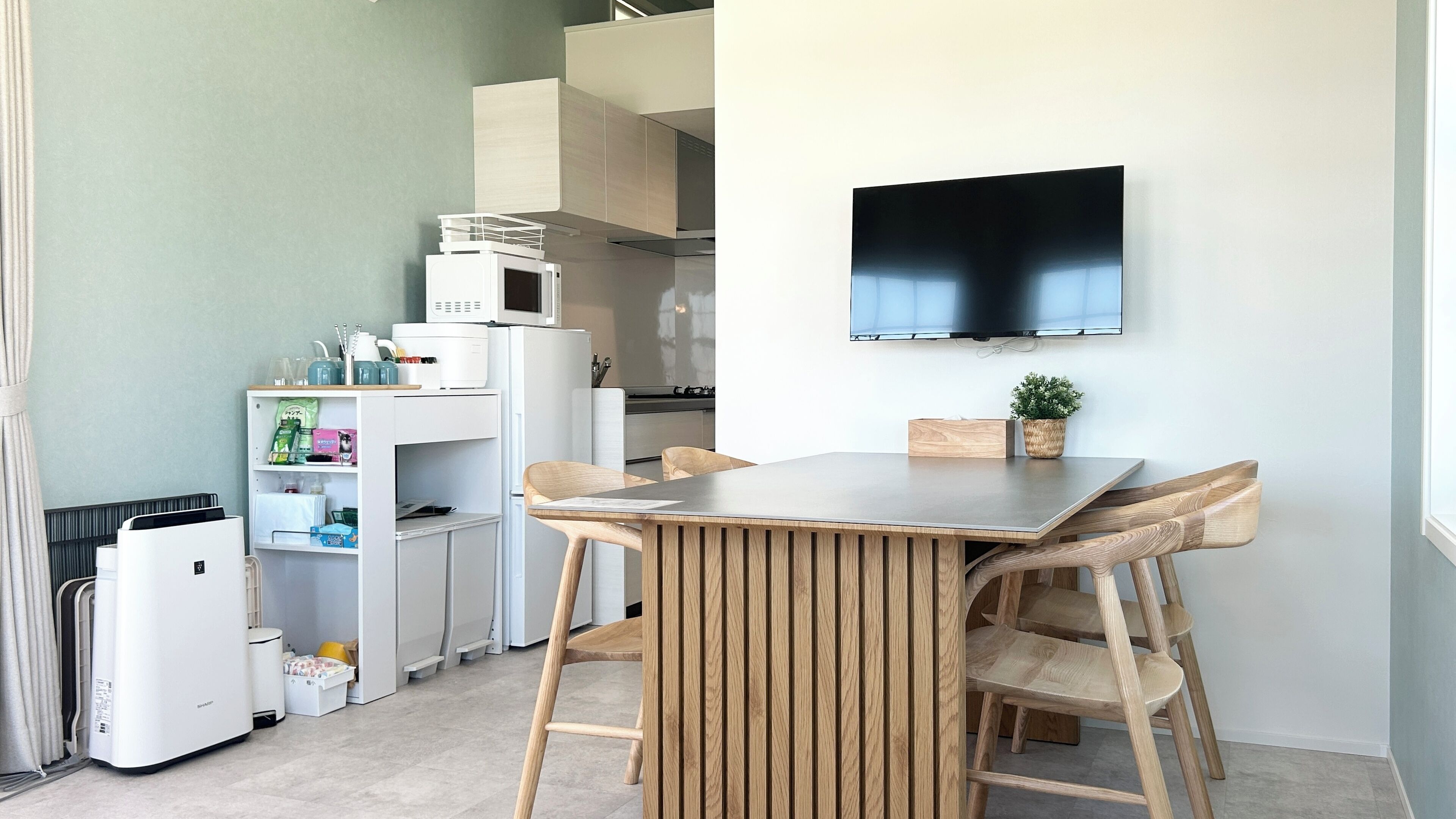 Una cocina compacta con comedor, microondas, refrigerador y un televisor de pantalla plana montado en la pared.