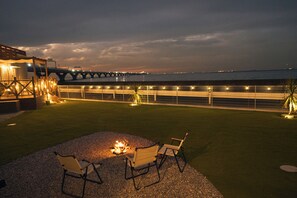 A patio with a fire pit and two chairs, overlooking a body of water and a bridge. - Solana Kisarazu (Kisarazu)