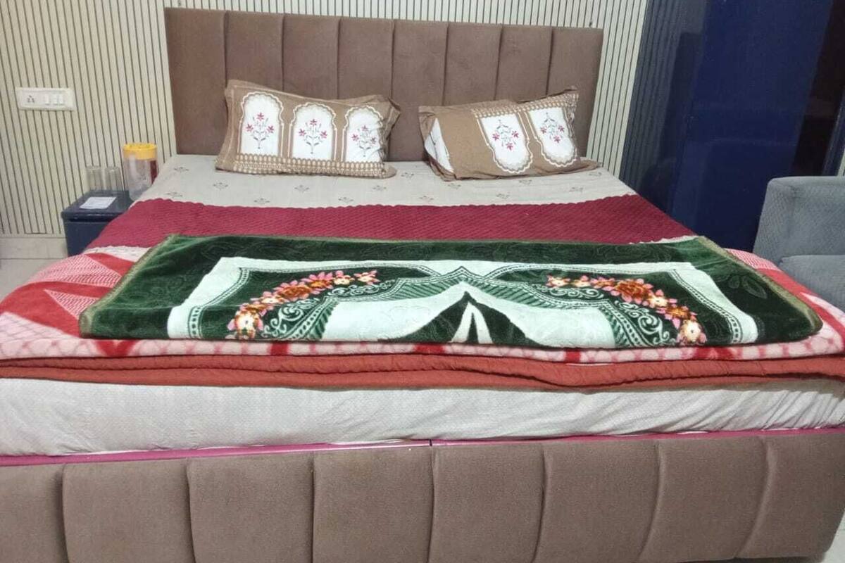 Un lit bien fait, avec une tête de lit marron, deux coussins décoratifs et une couverture à motifs floraux.