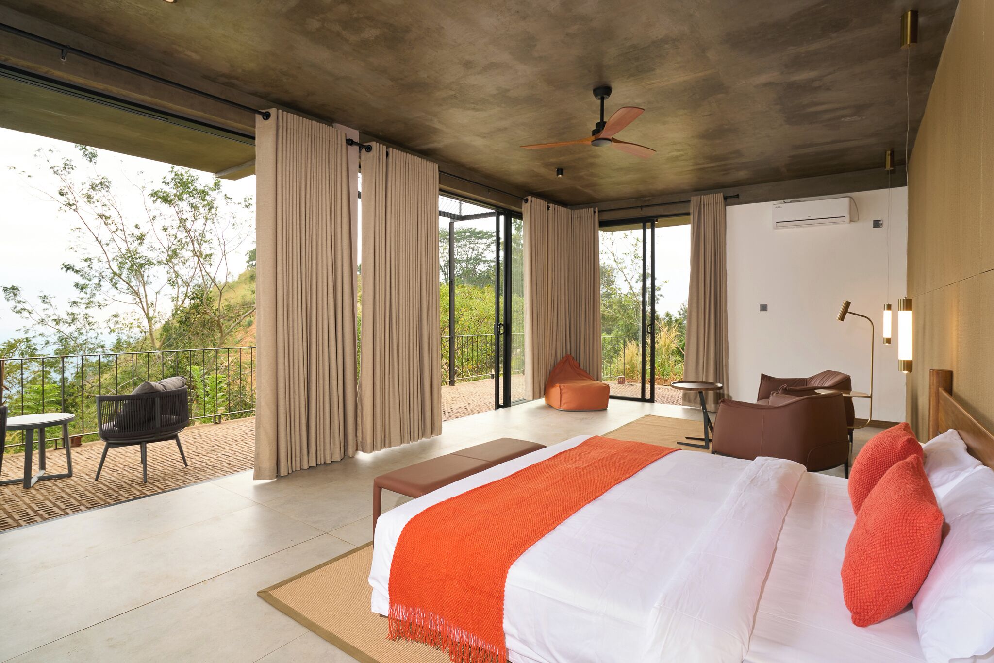 Una habitación de hotel moderna con una cama grande, un balcón y vistas al verdor.