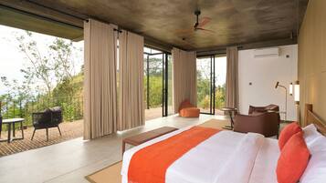Una habitación de hotel moderna con una cama grande, un balcón y vistas al verdor.