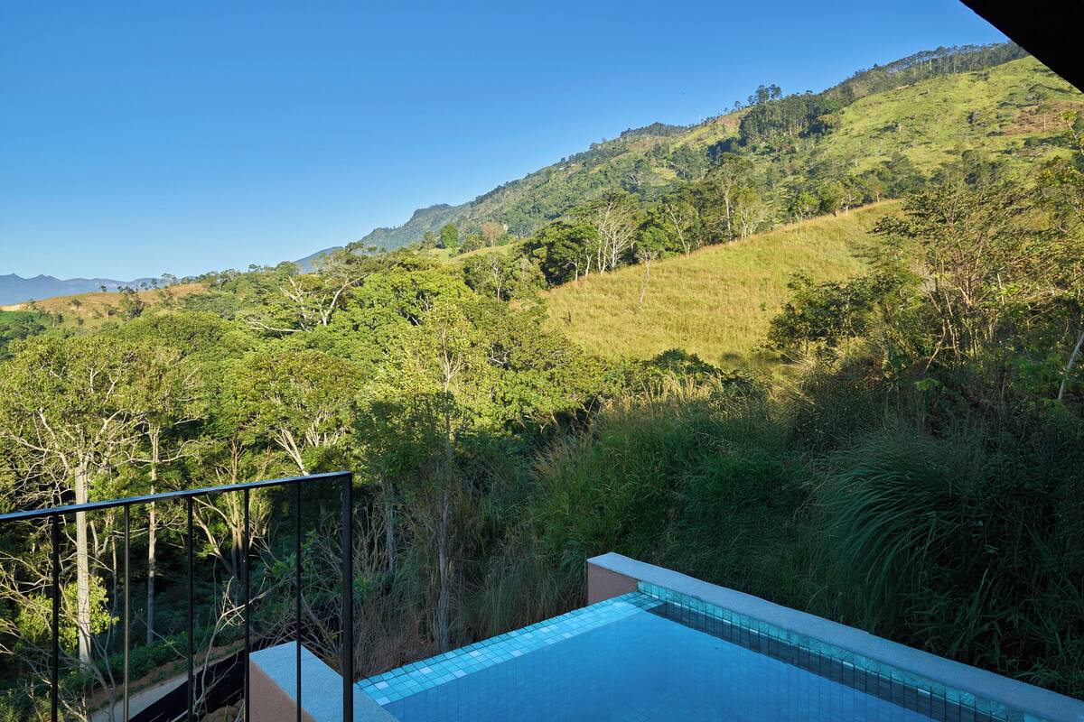 A pool with a view of a hillside and trees.