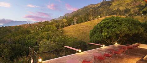 A terrace with outdoor seating and a view of a hilly landscape.