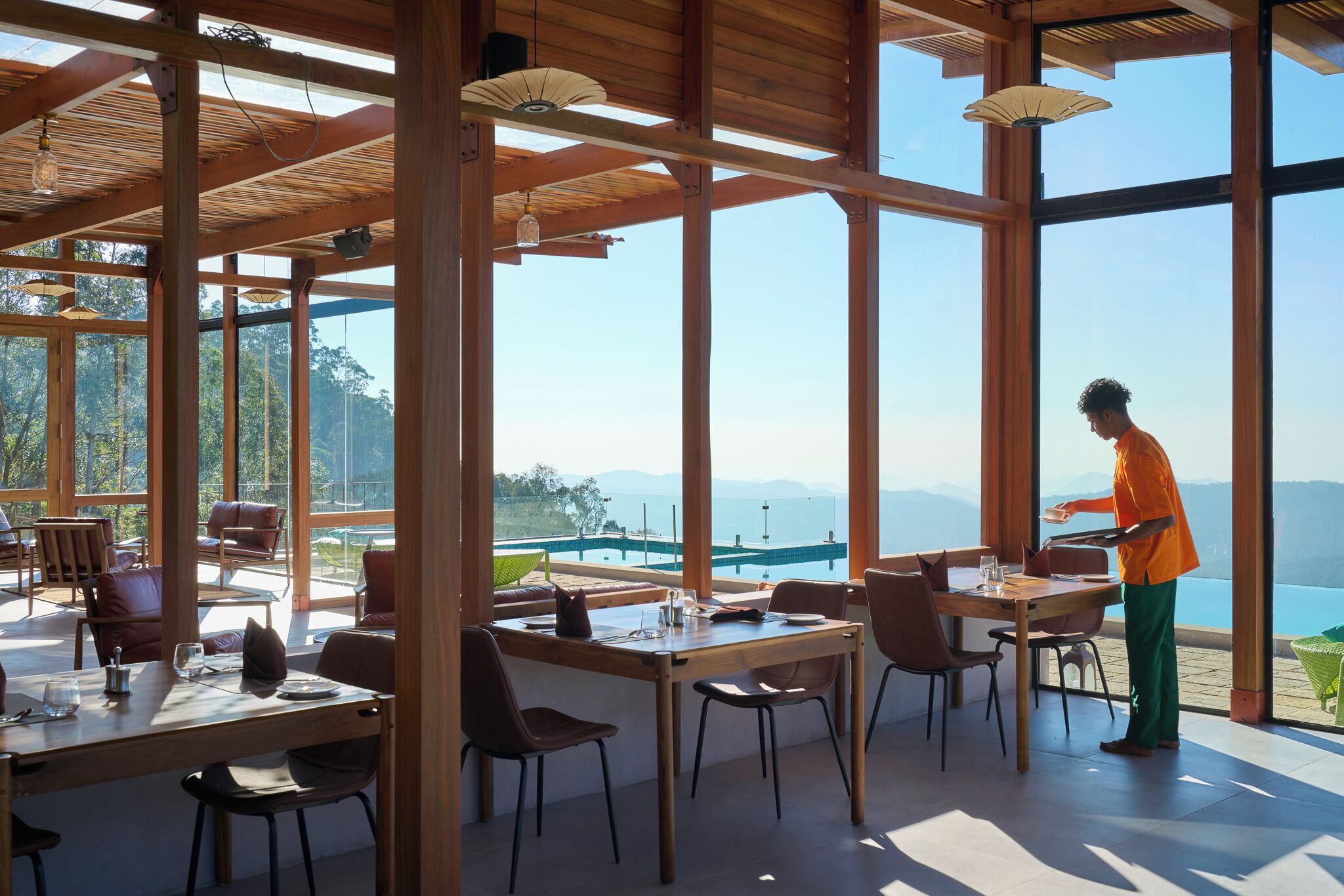 Un'ampia sala da pranzo con grandi finestre, travi in legno e vista sul mare.