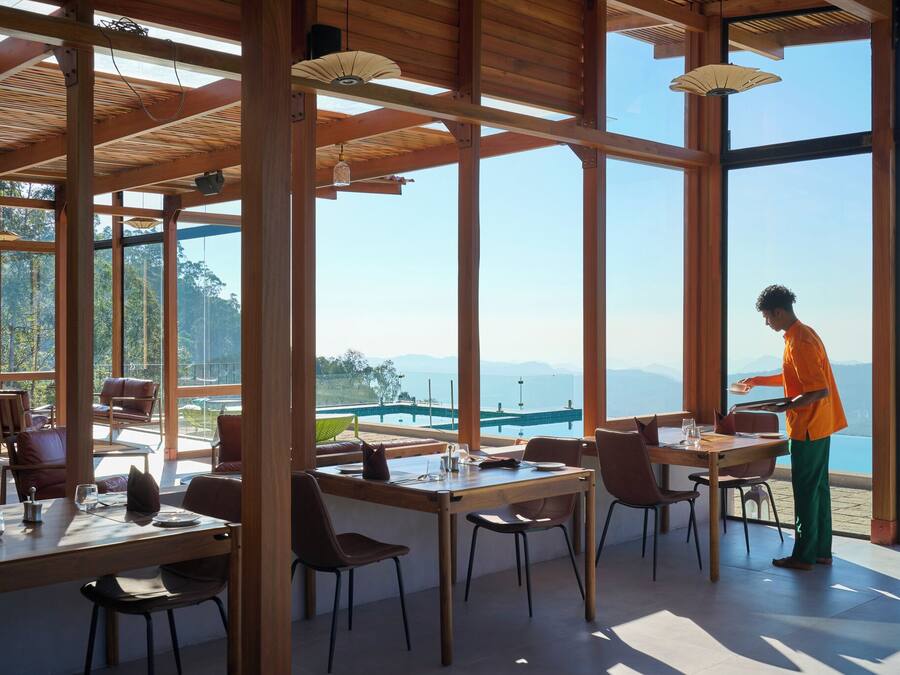 Un'ampia sala da pranzo con grandi finestre, travi in legno e vista sul mare.