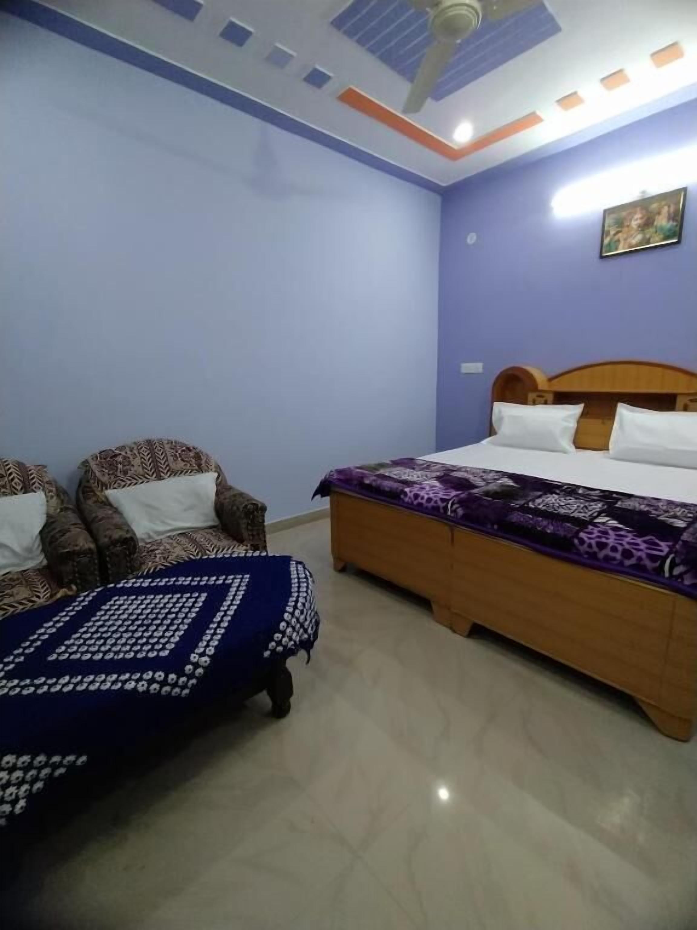 A bedroom with a bed, two sofas, and a ceiling fan.