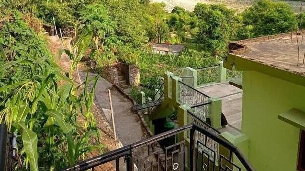 A view from a balcony overlooking a river, with a rainbow in the distance and lush greenery. - The Gangotri Homestay By Preet rS (Rajgarhi)