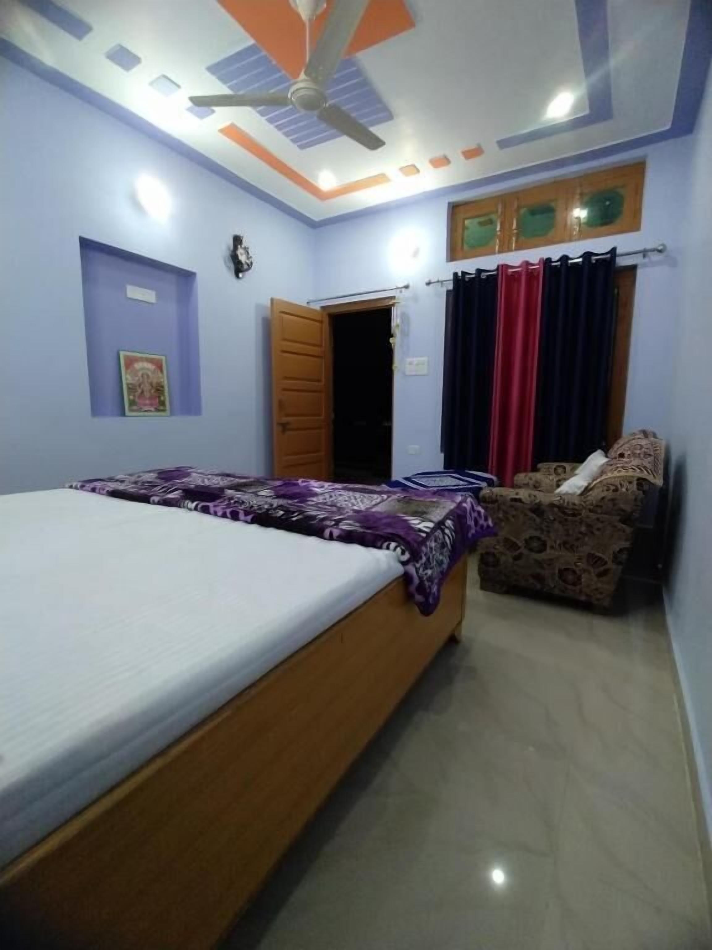 Un dormitorio con cama, sofá, ventilador de techo y ventana con cortinas.