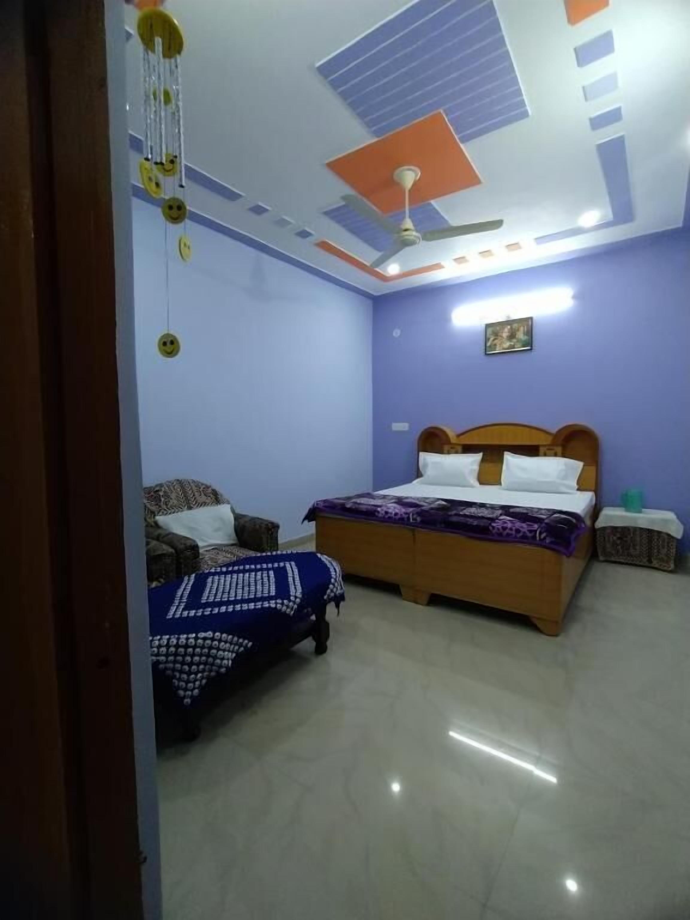 A bedroom with a bed, a nightstand, a ceiling fan, and a wall-mounted light fixture.