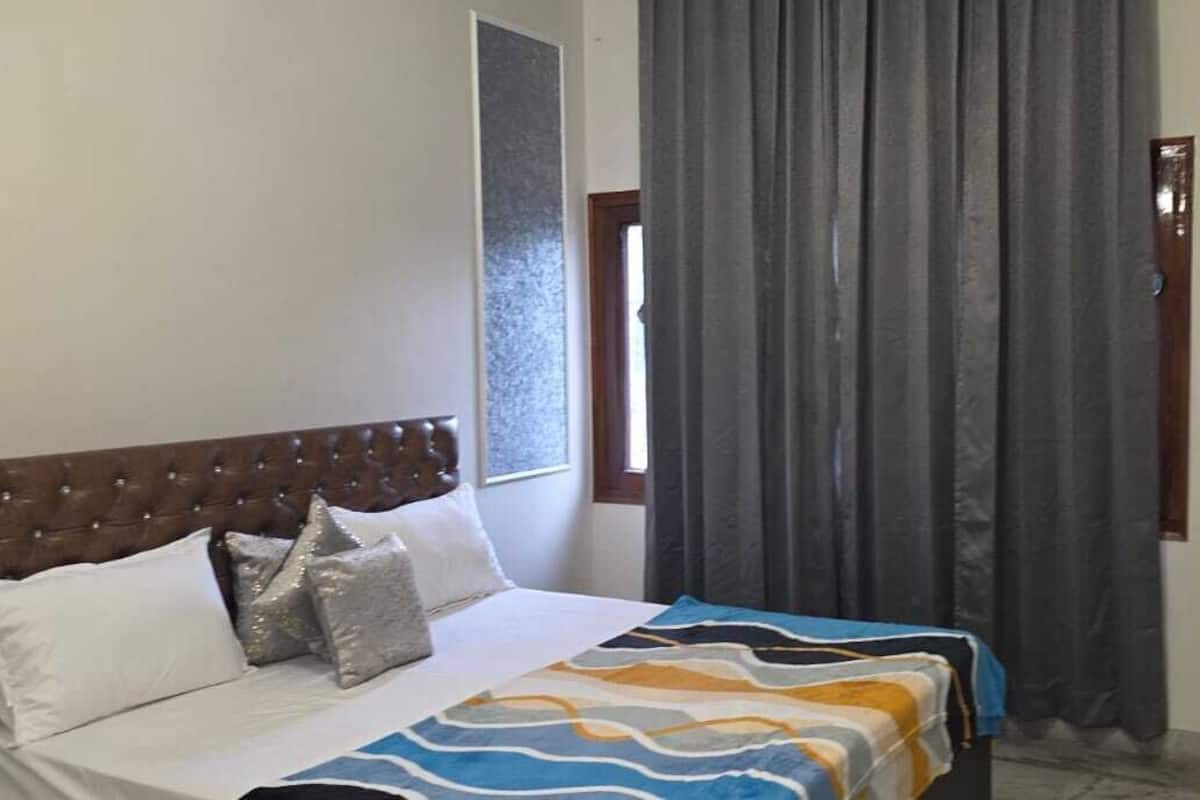 A bedroom with a bed, a headboard, and a window with curtains.