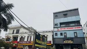 A multi-story building with a sign for a party hall, restaurant, and AC rooms on the upper floor.