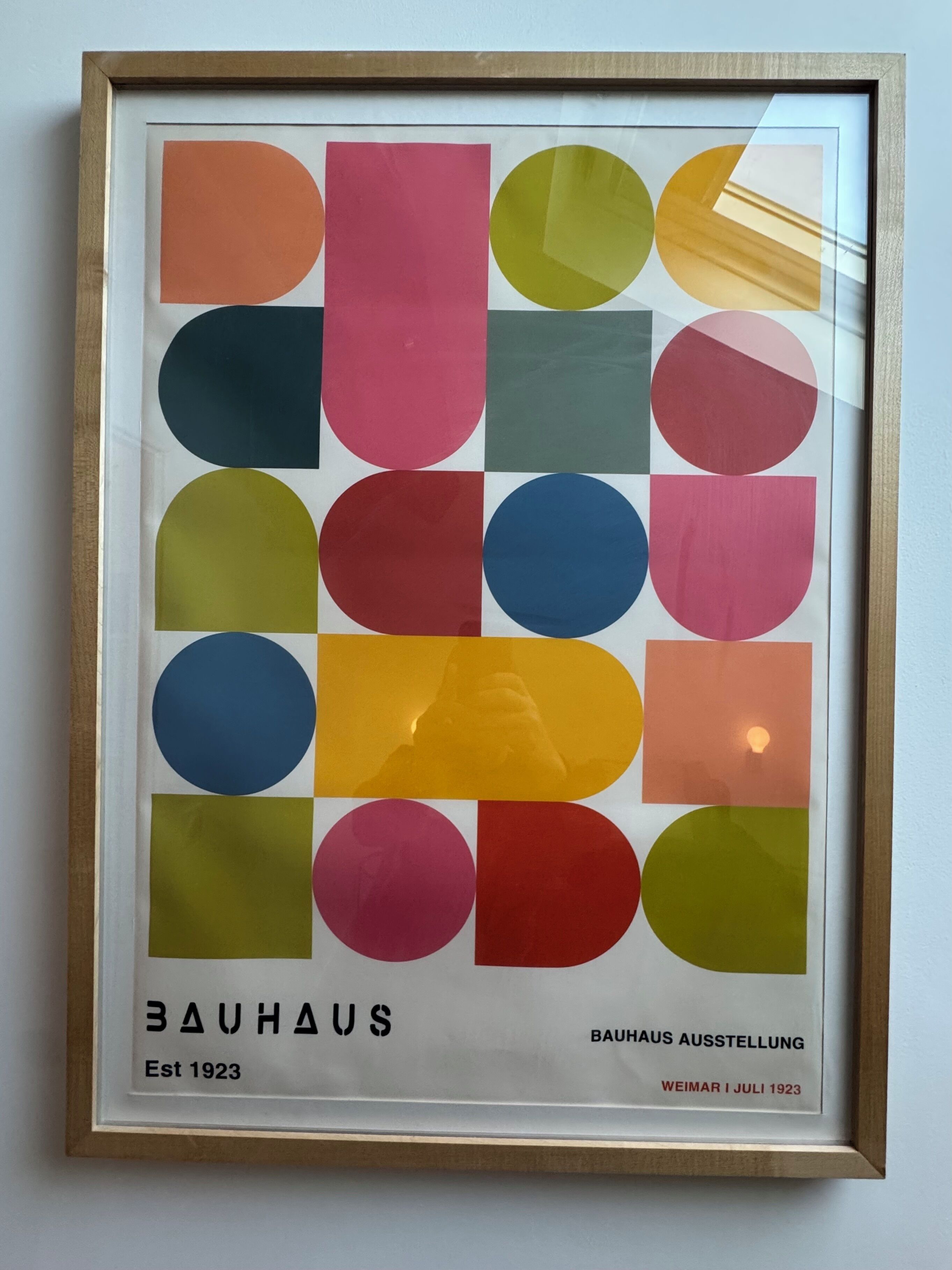 Una obra de arte enmarco con formas geométricas en varios colores, identificada como "Bauhaus" y "Est. 1923".