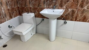 Ein Badezimmer mit Toilette, Bidet und Waschbecken an einer Marmorwand.