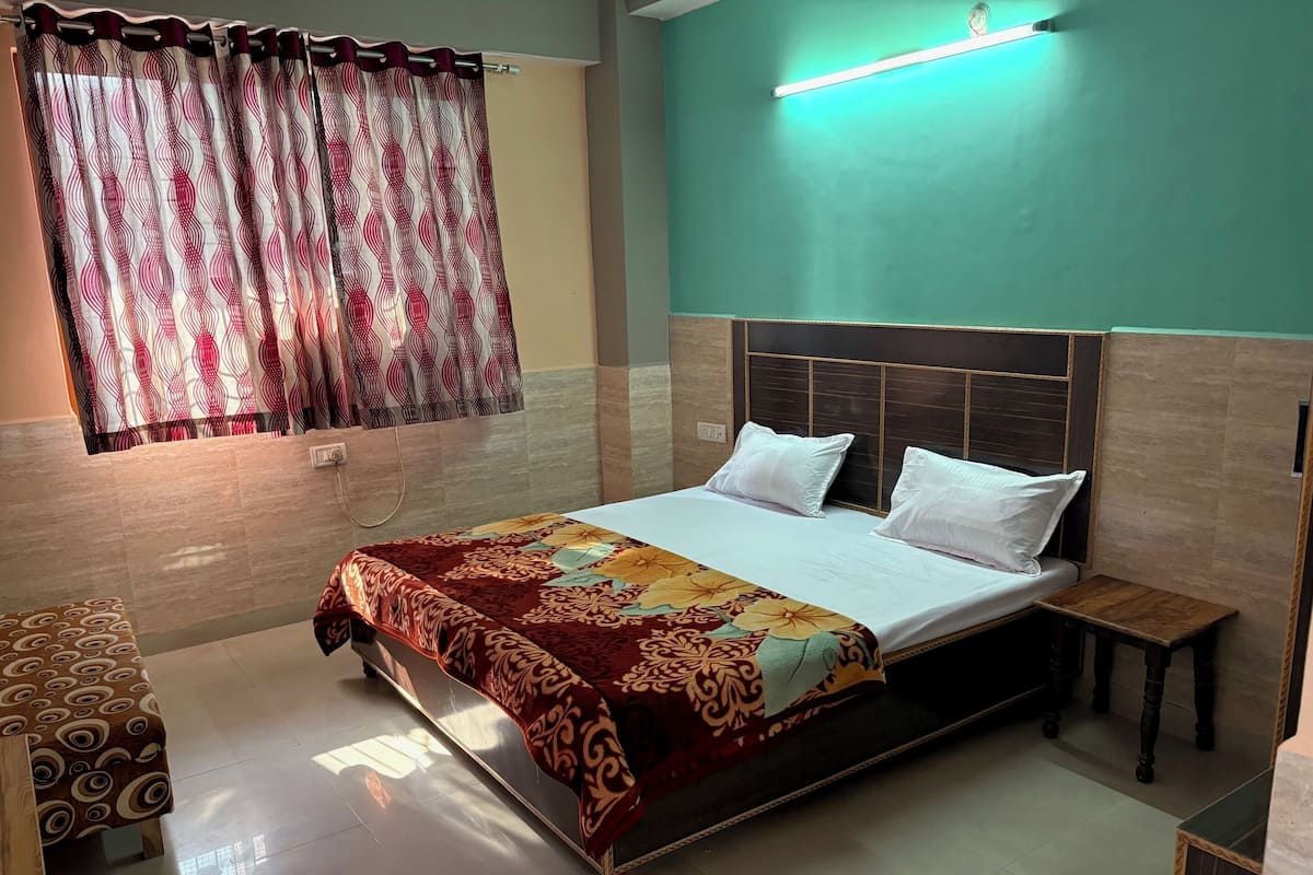 Un dormitorio ordenado con cama, mesitas de noche y una ventana con cortinas estampadas.