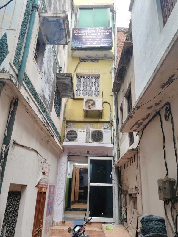 A narrow alleyway with a building featuring a sign for 'Riverview Haven Guest House & Cafe'. - Riverview Haven Guest House & Cafe (Varanasi)