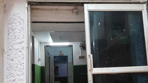 Un couloir doté d’un sol carrelé, une porte donnant sur une pièce et une fenêtre offrant une vue sur l’extérieur.