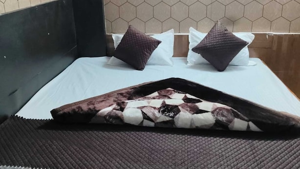 Un lit avec une couvre-lit à motifs, deux oreillers et une tête de lit.