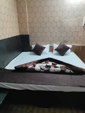 Ein Bett mit einem gemusterten Überwurf, zwei Kissen und einem Kopfteil.