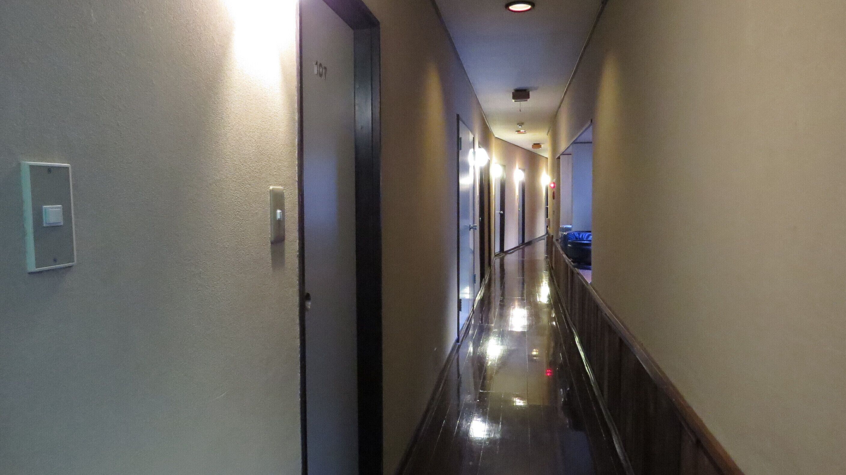 A hotel hallway with a polished floor, light switches, and a door marked with the number 107.