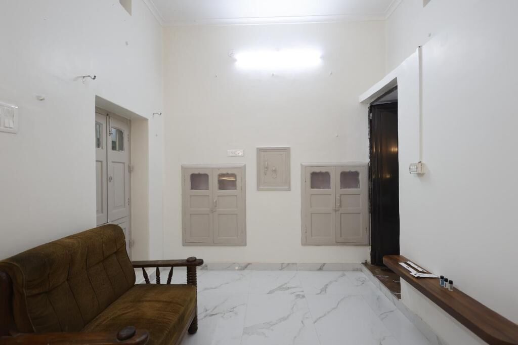 Um corredor com um sofá marrom, paredes brancas e chão de mármore.