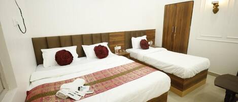 A hotel room with two single beds, a wooden wardrobe, a desk, and a chair.
