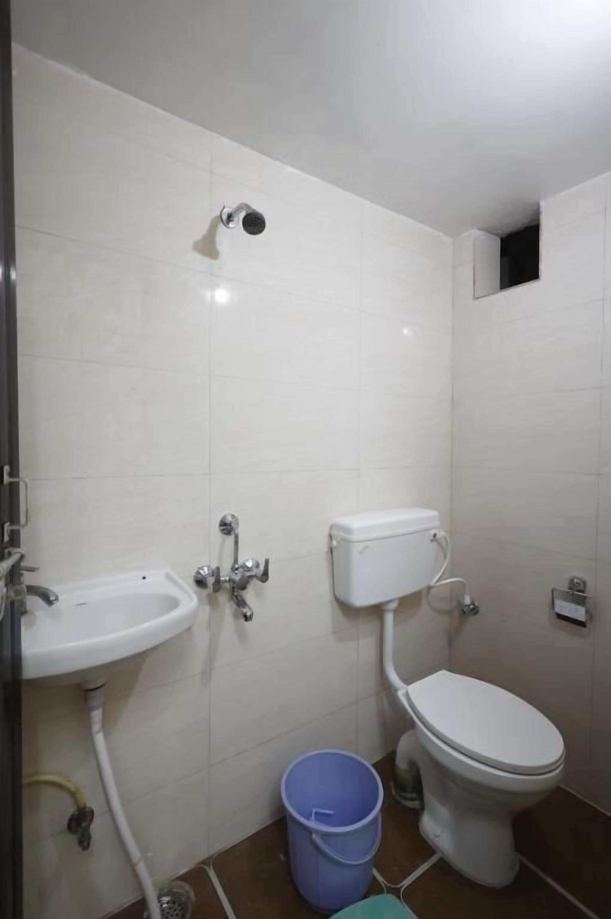 Uma casa de banho pequena com lavatório branco, sanita e chuveiro.