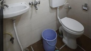 Uma casa de banho pequena com lavatório branco, sanita e chuveiro.