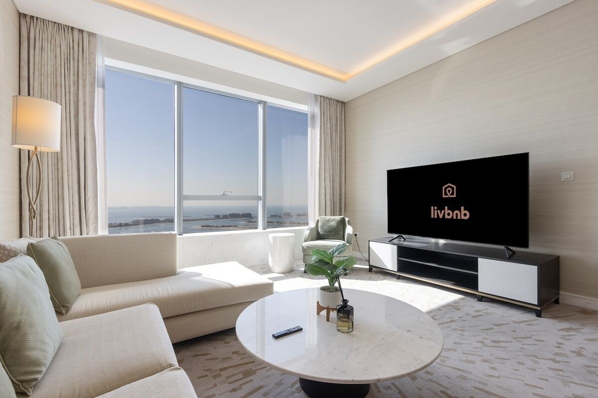 A modern living room with a large TV, a sofa, a coffee table, and a view of the city.