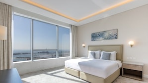 Habitación de hotel moderna con una cama grande, vista al mar y al paisaje urbano.