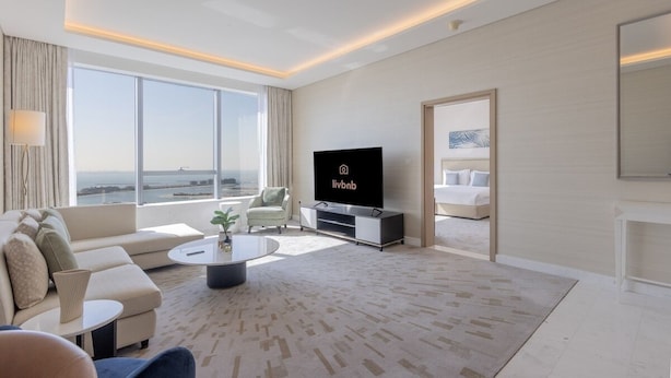 Una habitación de hotel moderna con un gran ventanal, un televisor de pantalla plana, un sofá, una mesa de centro y una cama.