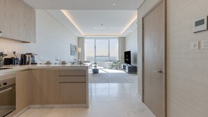 Una cocina moderna con una isla central, un área de comedor con sofá y televisor, y un ventanal con vistas.