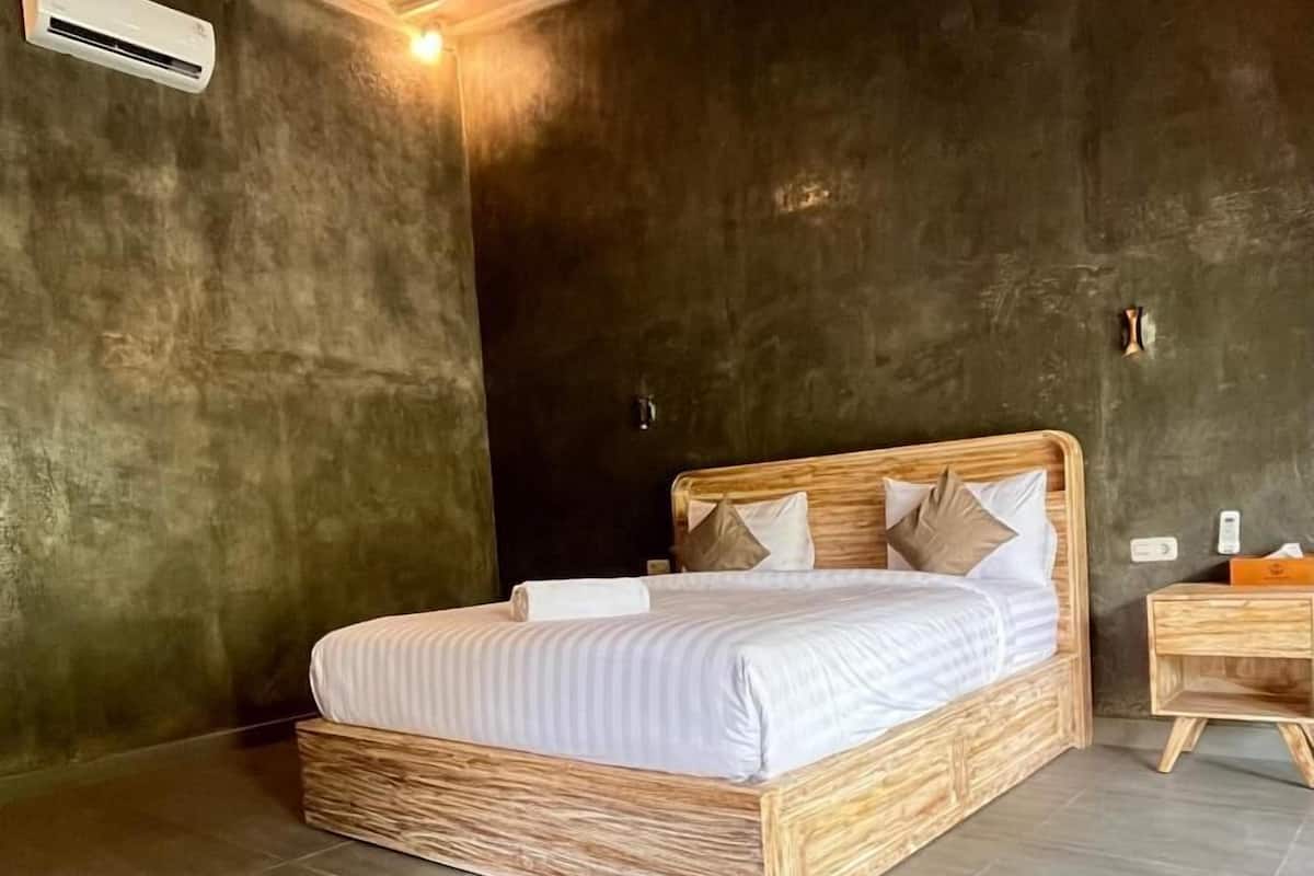 Een slaapkamer met een houten bed, een nachtkastje en een airconditioner.