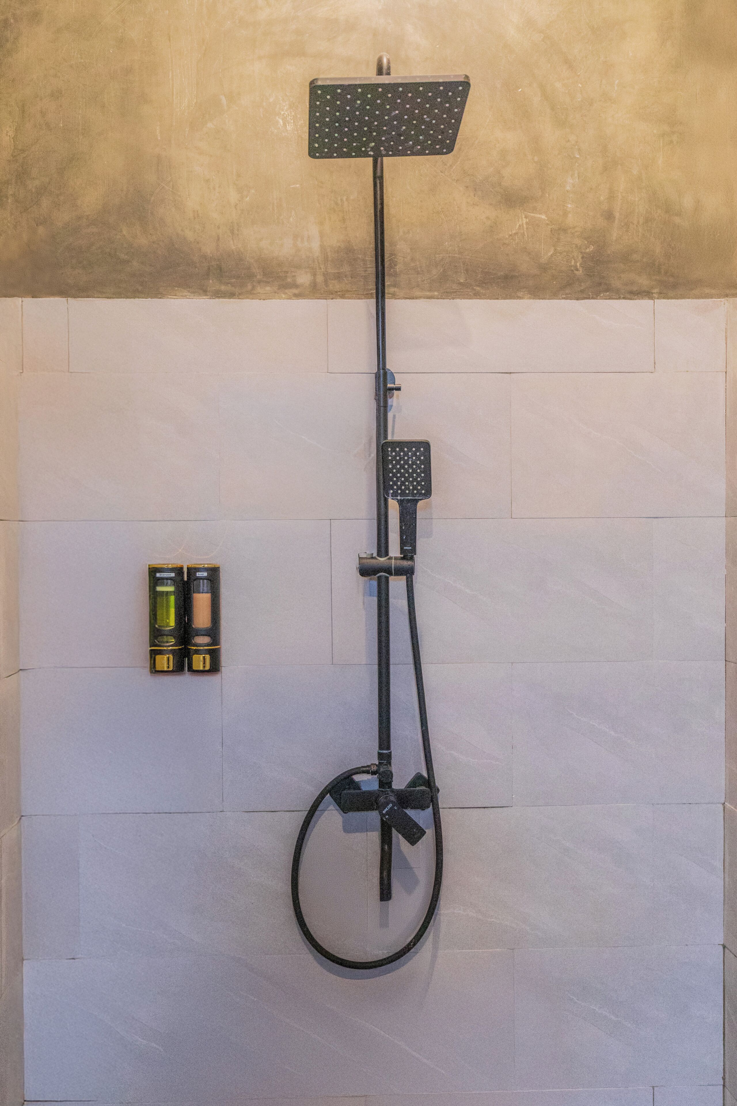 A shower with a handheld attachment, a handheld showerhead, and a wall-mounted control panel.