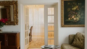 Habitació amb un sòl en disseny de petxina d'atzó, un armari de fusta, una taula rodona amb revistes, un sofà estampat, un mirall amb marc ornamentat i un quadre al mur.