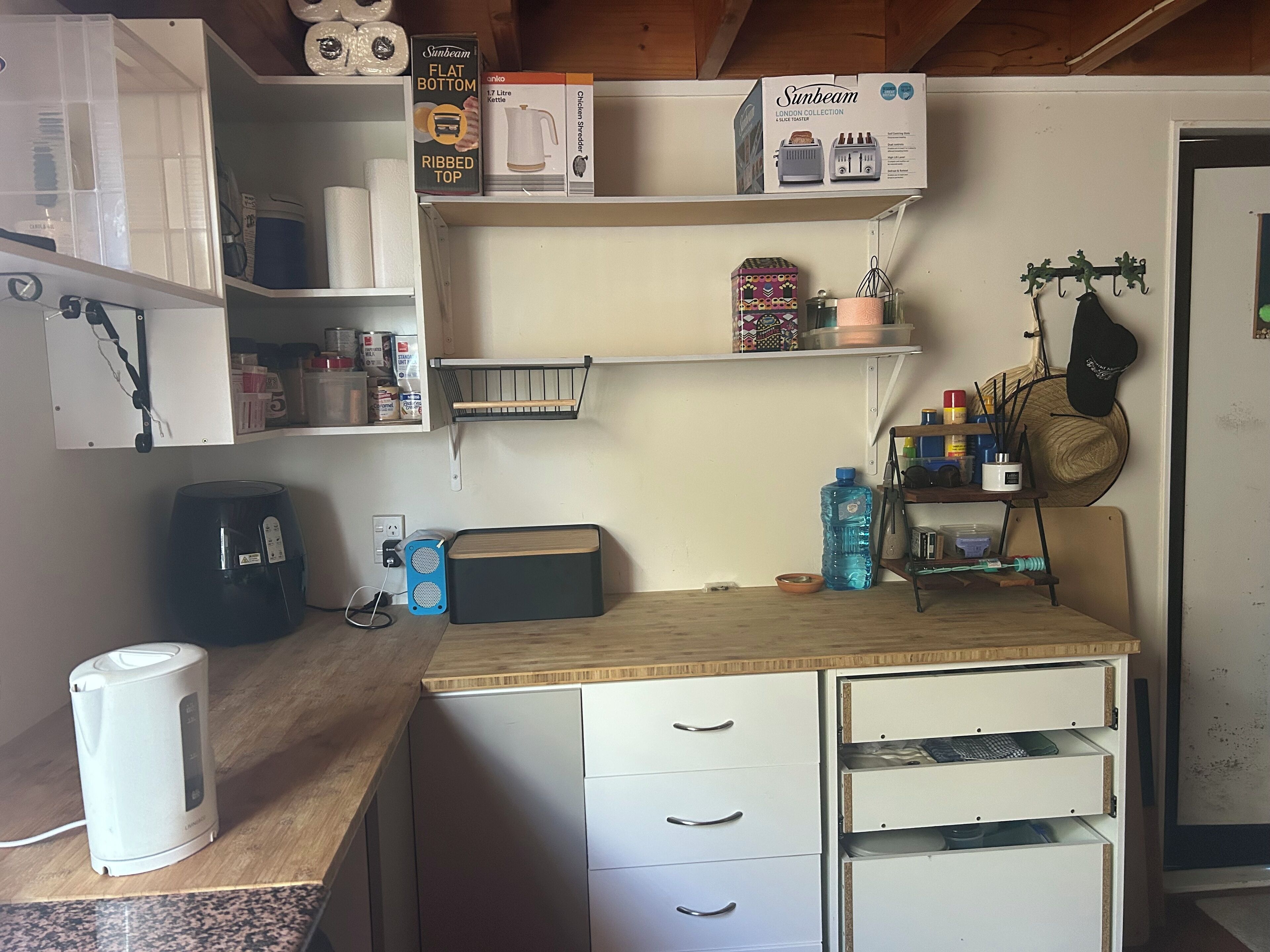 Une cuisine dotée d’un plan de travail en bois, de meubles blancs et de divers appareils de cuisine, notamment une bouilloire, une machine à café et un grille-pain.