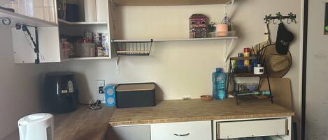 Une cuisine dotée d’un plan de travail en bois, de meubles blancs et de divers appareils de cuisine, notamment une bouilloire, une machine à café et un grille-pain.