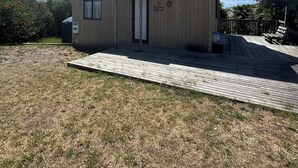 Ein zweistöckiges Holzhaus mit Flachdach, Eingangstür und kleiner Veranda.