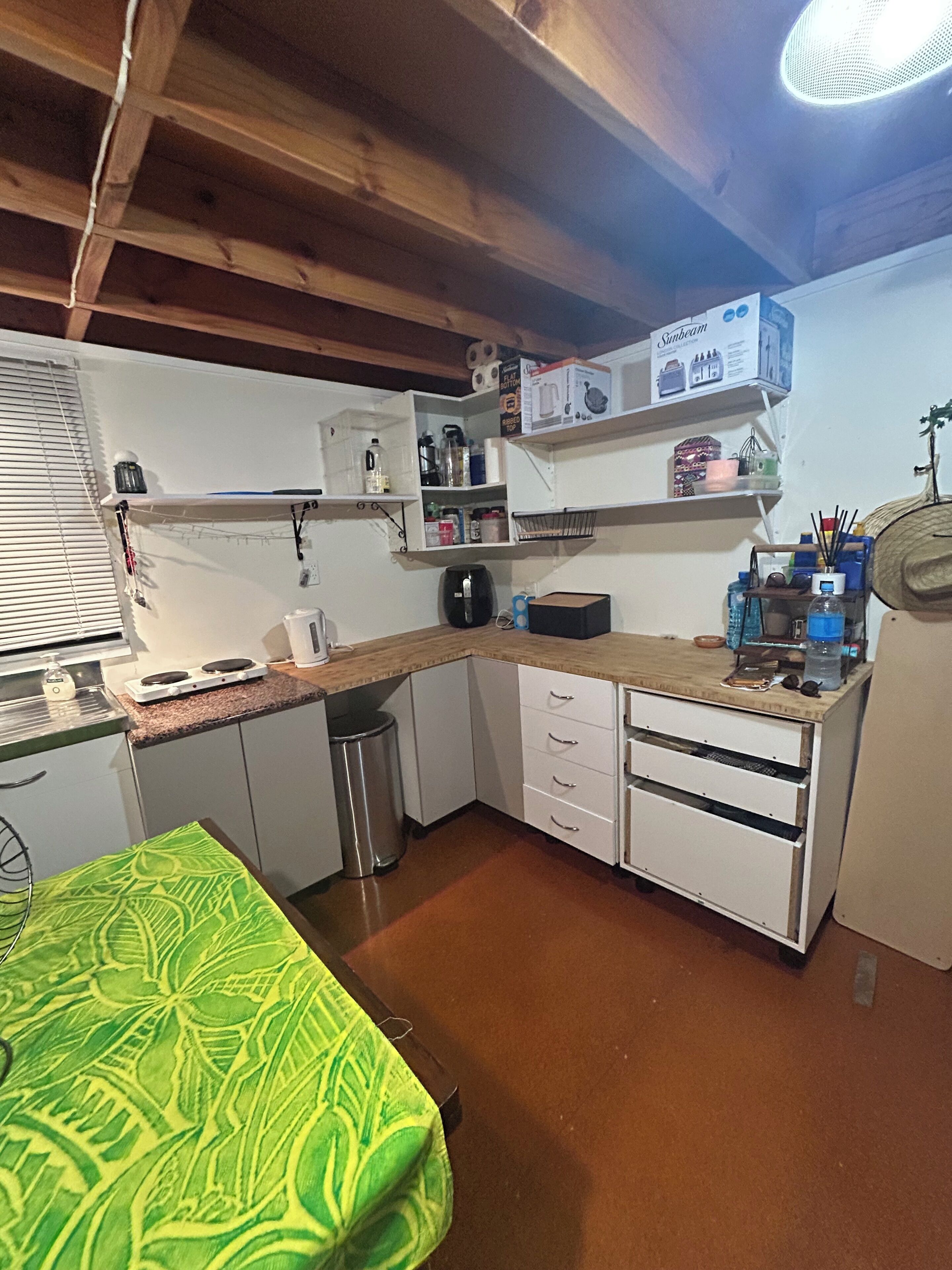 Una cocina compacta con armarios blancos, encimera de madera y un pequeño cubo de basura.