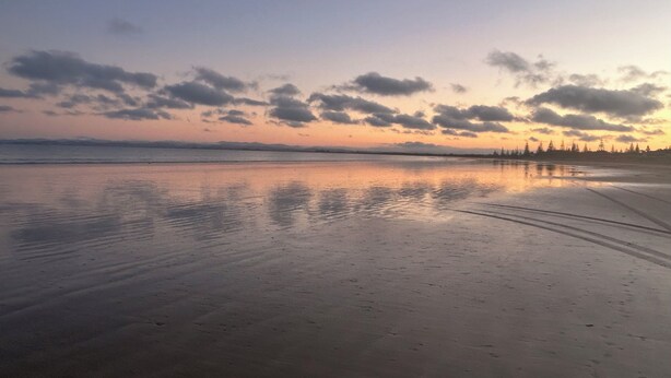 Ein Strand mit ruhiger See und blauem Himmel.