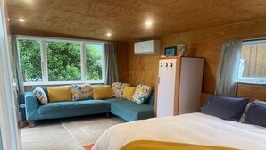 A bedroom with a bed, a sofa, a wardrobe, and a window with curtains.