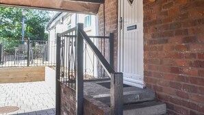 A brick exterior with a white door, a metal staircase, and a wooden deck area. - A beautifully restored single-storey two bedroom cottage sleeping four people. (Filey)