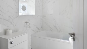A bathroom with a marble wall, a toilet, a sink, and a bathtub. - A beautifully restored single-storey two bedroom cottage sleeping four people. (Filey)