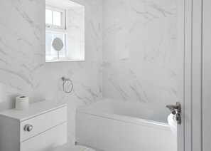 A bathroom with a marble wall, a toilet, a sink, and a bathtub. - A beautifully restored single-storey two bedroom cottage sleeping four people. (Filey)