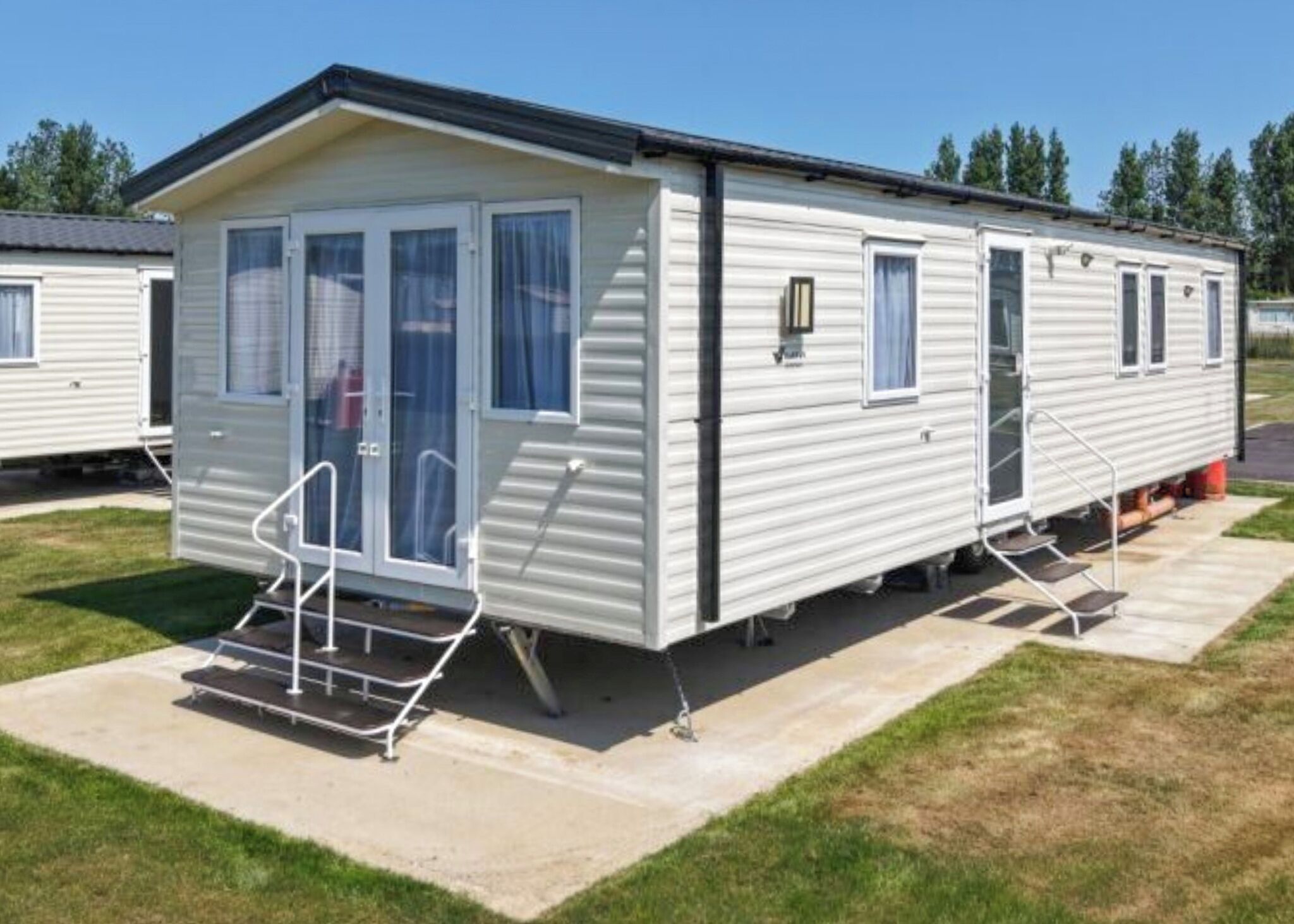 A mobile home with a front porch, a sliding door, and a small attached garage.