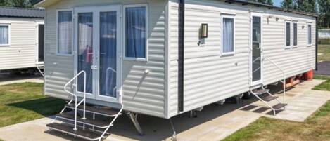 A mobile home with a front porch, a sliding door, and a small attached garage.
